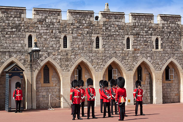 Windsor, United Kingdom - June 29, 2015: Changing the Guard at Windsor Castle, Berkshire England. Windsor castle was built in the 11th century and is the longest-occupied palace in Europe. Guards wearing vivid red uniform and carrying rifles are in the image. 