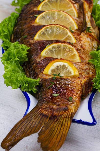 istock Whole grilled fish carp served with salad and lemon 517338670