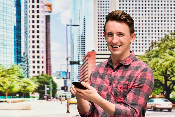 istock Smiling casual man using phone outdoor 517339578