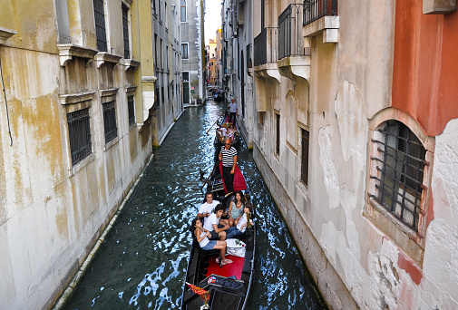 Venice, Italy - July 21, 2010: Gondolier runs the gondola with group of tourists on the Venetian canal in Venice, Italy.