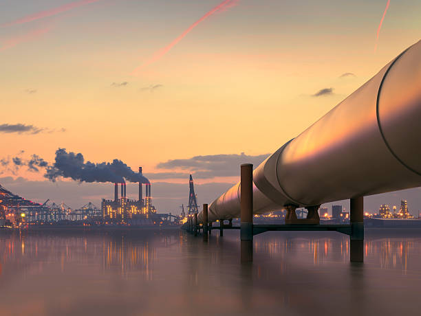 Oil pipeline in industrial district with factories at dusk Pipeline in industrial district crude oil stock pictures, royalty-free photos & images