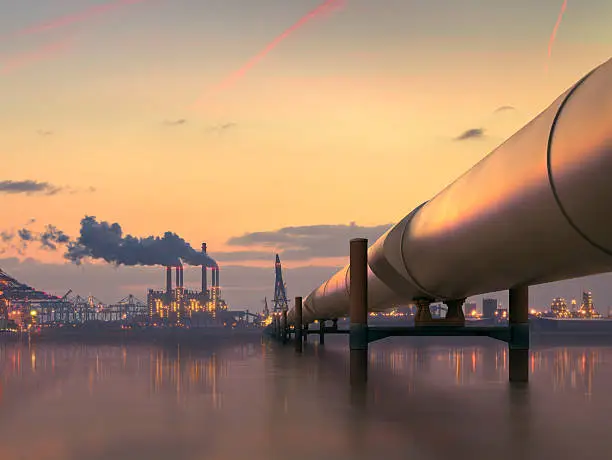 Photo of Oil pipeline in industrial district with factories at dusk