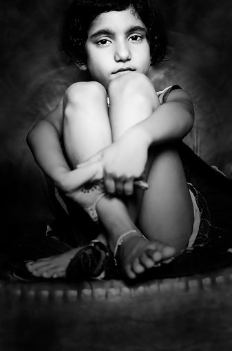 portrait of small girl sitting with folded arms leg on chair
