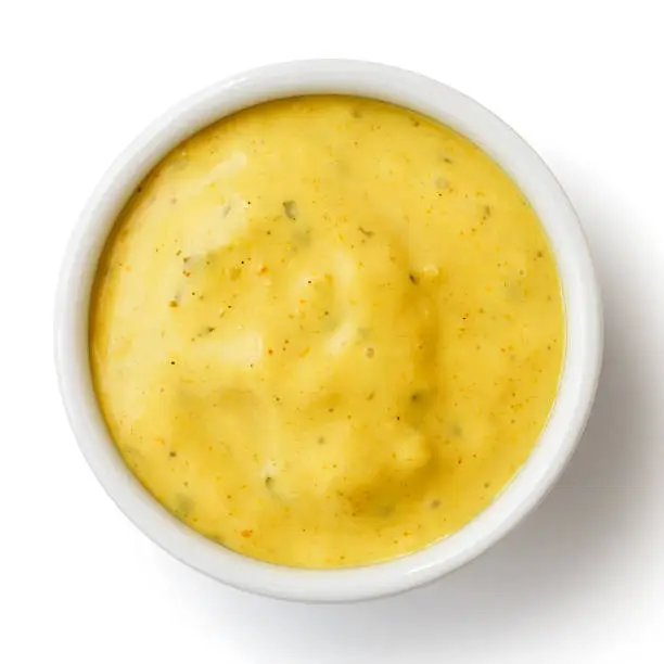 Small condiment bowl of yellow curry sauce. Isolated on white from above.