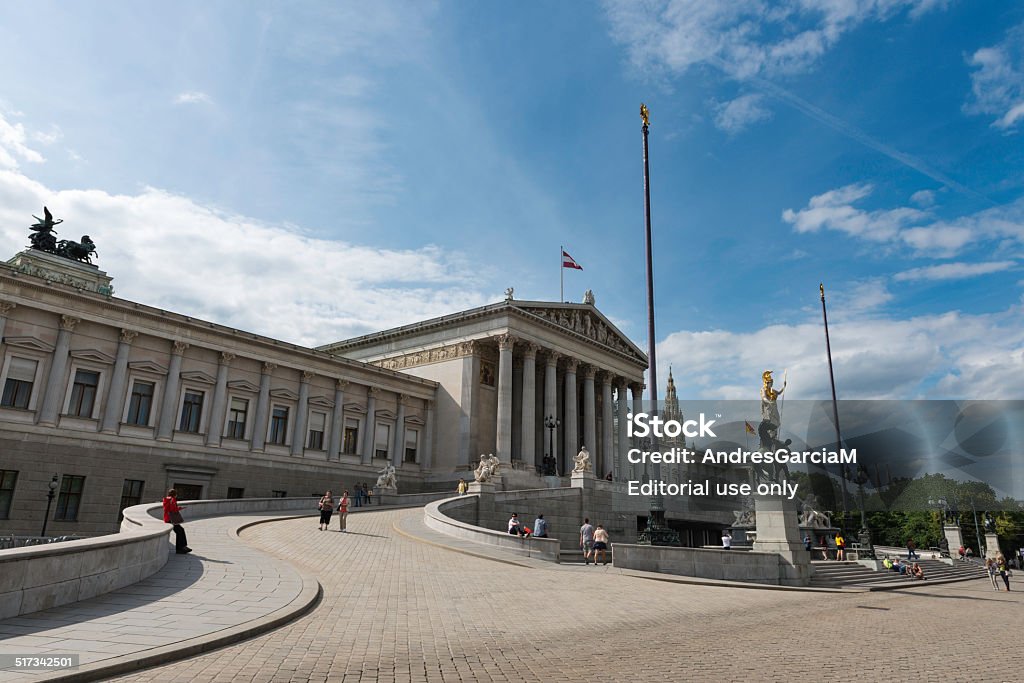 Classic architecture at the Austrian Parliament Building in Vienna Vienna, Austria - June 21, 2014: Tourists walking and resting  around the Austrian Parlament building (Parlamentsgebäude) in Vienna on a sunny Spring afternoon. Located on the Ringstrasse boulevard, the building was completed in 1883 in Greek Revival style. Architectural Column Stock Photo