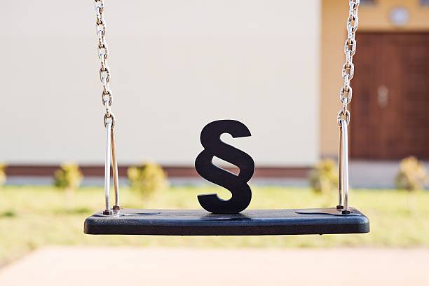 Black paragraph symbol on children chain swing. Black paragraph symbol on children chain swing. Family law or playground accident concept. schoolyard fight stock pictures, royalty-free photos & images