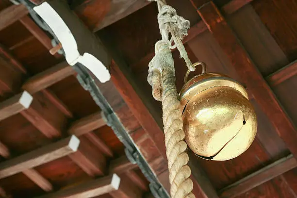 a bell and rope hanging in an old japanese temple for peopole praying