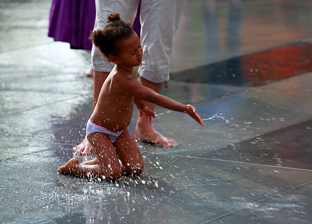 Paris, France - September 07, 2014 : Little girl playing with water in a puddle of Republic Square on weekend on sep 07. 2014 in Paris, France.