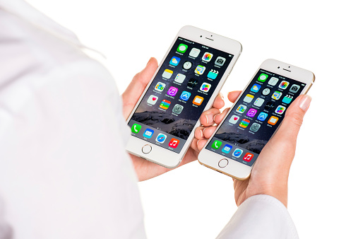 Koszalin, Poland - October 07, 2014: Close-up shot of iPhone 6 and iPhone 6 Plus hand-held by woman. iPhone 6 (4.7 inches) and 6 Plus (5.5 inches) are next generation smartphone from Apple. Devices displaying the applications on the home screen.