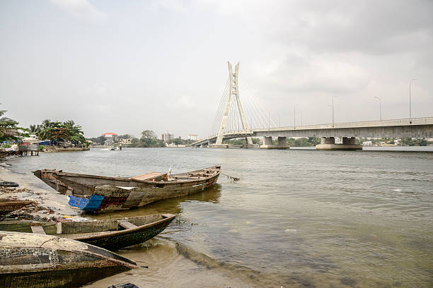 Lekki Ikoyi Bridge with fishing boat, Lagos, Nigeria The old and new are contrasted with wooden fishing boat moored on Five Cowries Creek below the Lekki Ikoyi Link Bridge, Lagos, Nigeria. lagos nigeria stock pictures, royalty-free photos & images