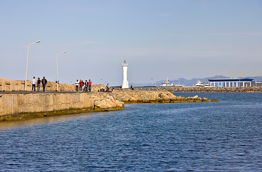 Kyrenia, Cyprus - March 12, 2016: Photo of the waterfront and harbour with jetty in Kyrenia, Northern Cyprus. People are visiting the harbour for touristic, some of them eating for dinner, some of them are resting near the sea in the Old Harbour in Kyrenia (Girne), Cyprus.