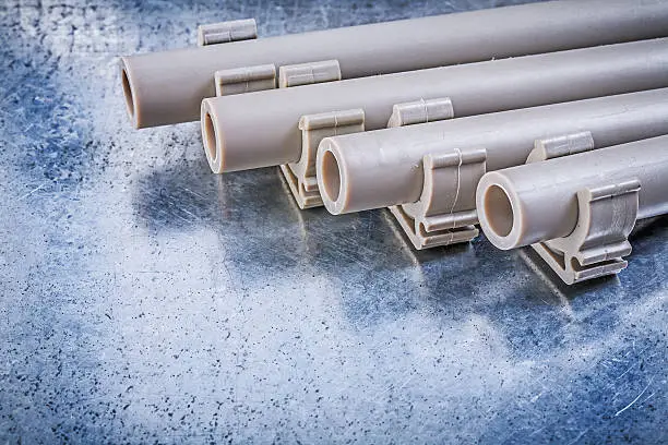 Pvc water-pipes pipe clamps on metallic background construction concept.