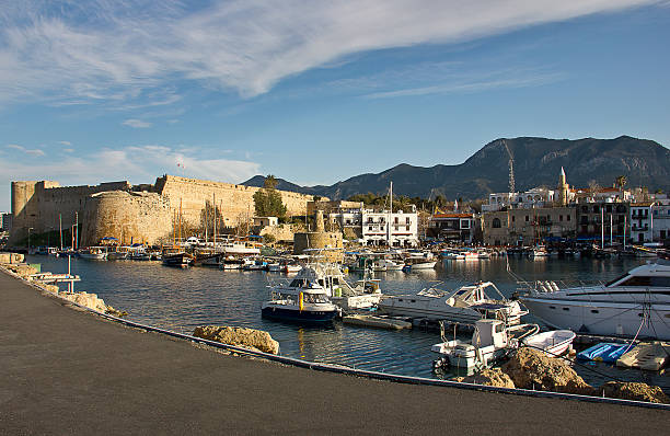 Kyrenia, Cyprus - March 12, 2016: Photo of the waterfront and harbour with sailboats in Kyrenia, Northern Cyprus. People are visiting the harbour for touristic, some of them eating for dinner, some of them are resting near the sea in the Old Harbour in Kyrenia (Girne), Cyprus.