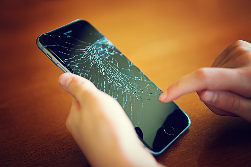 Sofia, Bulgaria - May 17, 2015: Broken Iphone 6 still working. On the photo is my 12 years old daughter. She is holding her broken /after fell down from her bicycle/ Iphone 6. The phone screen is crashed but the phone was still working. The image was taken at the 17th of May 2015 at the same day when she fell down from her bicycle and broke her Iphone. The image was taken in the our home in Sofia, Bulgaria.