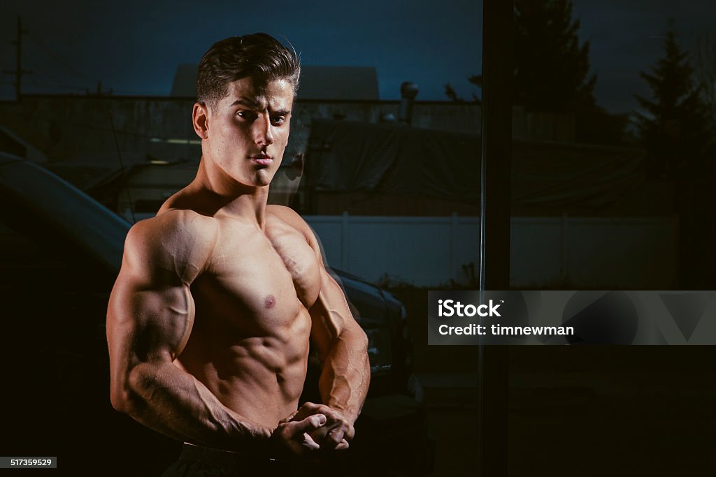 Attractive Young Strong Male Body Builder Flexing Studio portrait of a fit male model flexing at the Gym Abdomen Stock Photo