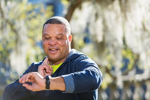 Mature man (50s) exercising in park, checking his pulse.
