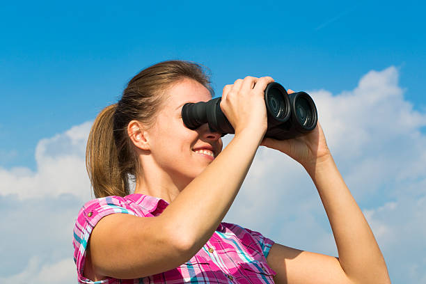 istock Cute young woman looking through binoculars 517360301