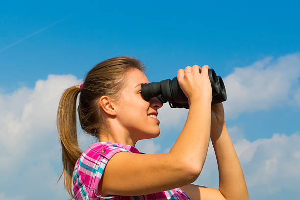 istock Cute young woman looking through binoculars 517360477