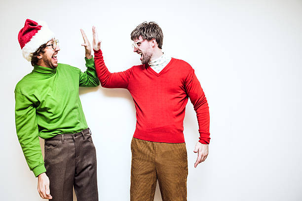 Christmas Nerd High Five Two goofy looking men in ugly Christmas colored turtlenecks and sweaters give each other a high five to celebrate the holiday season.  Horizontal image with some copy space. christmas ugliness sweater nerd stock pictures, royalty-free photos & images