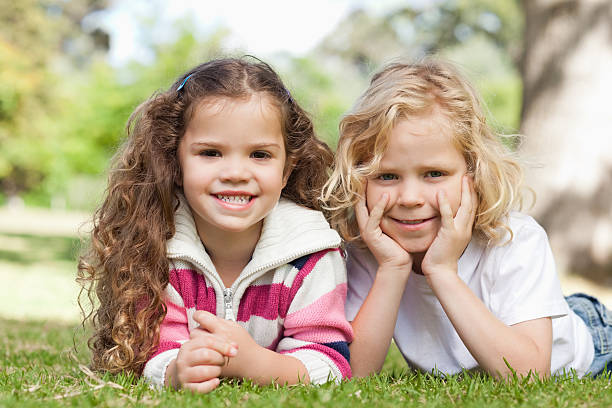 istock Two friends smiling as they lie on the grass together 517361111