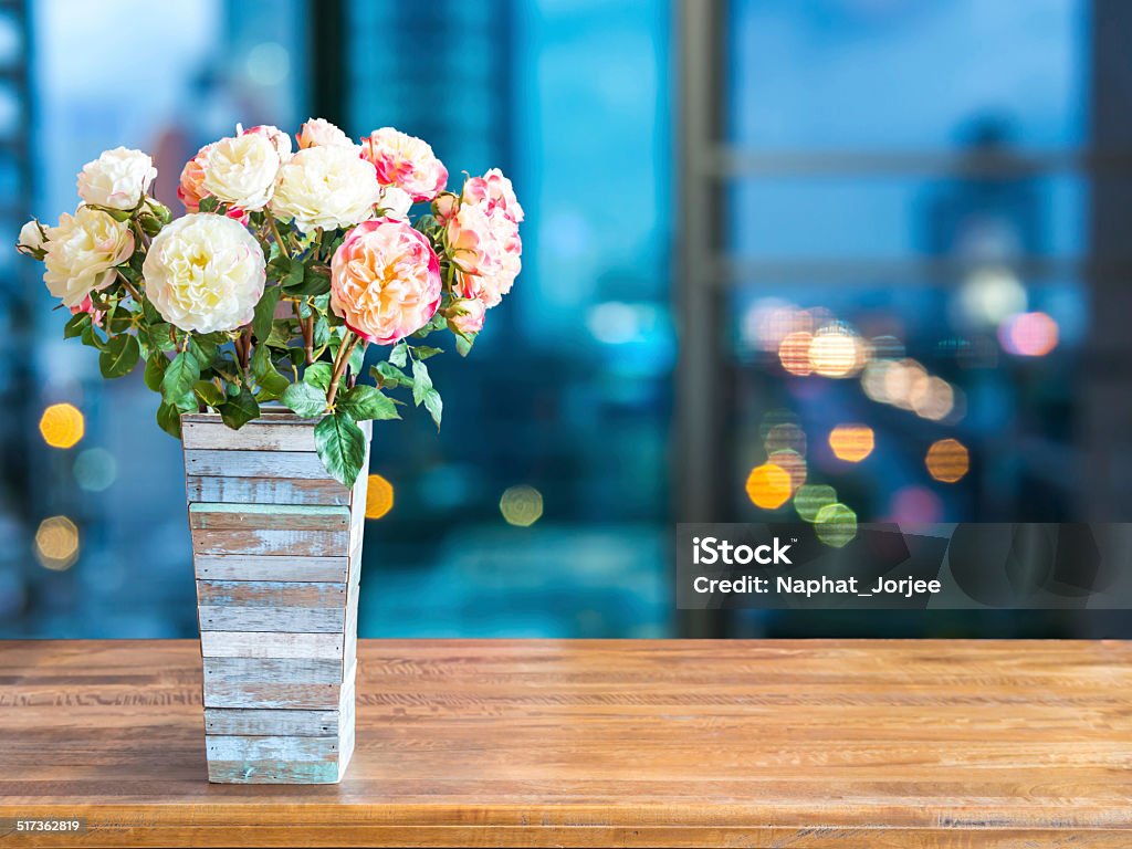 Flower vase on tabletop with blurred modern cityscape night background Flower vase on rustic tabletop with abstract blurred modern cityscape night background Abstract Stock Photo