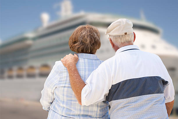 senior coppia sulla spiaggia guardando nave da crociera - nave di passeggero foto e immagini stock
