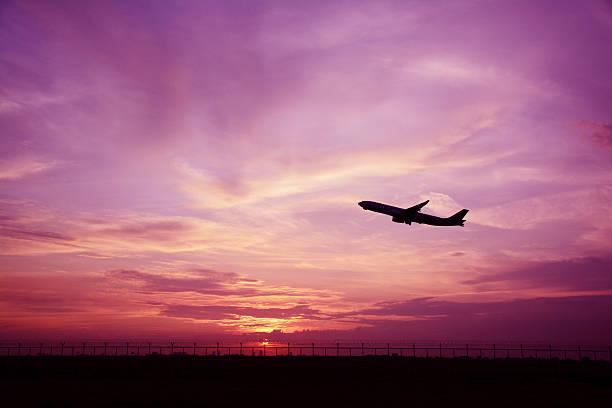 Silhouette of airplane on sunset background.