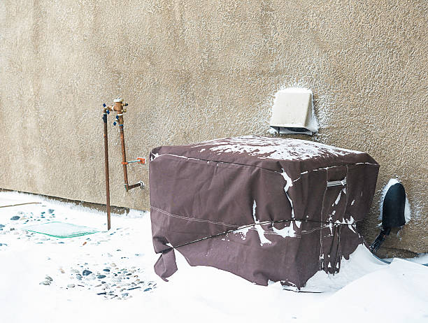 Residential air conditioning unit wrapped with protective cover in blizzard