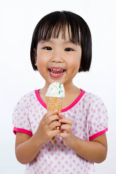Asian Little Chinese Girl Eating Ice Cream Asian Little Chinese Girl Eating Ice Cream isolated on White Background asian little chinese girls eating ice cream stock pictures, royalty-free photos & images