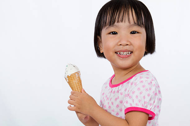 Asian Little Chinese Girl Eating Ice Cream Asian Little Chinese Girl Eating Ice Cream isolated on White Background asian little chinese girls eating ice cream stock pictures, royalty-free photos & images