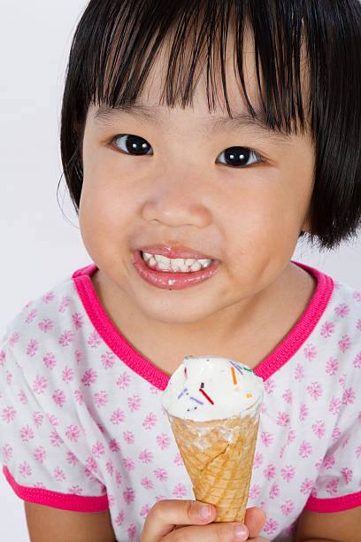 Asian Little Chinese Girl Eating Ice Cream Asian Little Chinese Girl Eating Ice Cream isolated on White Background asian little chinese girls eating ice cream stock pictures, royalty-free photos & images