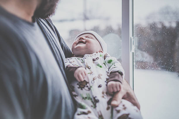 liebenden vater mit neugeborenen baby in der nähe der fenster im winter - incoming storm stock-fotos und bilder