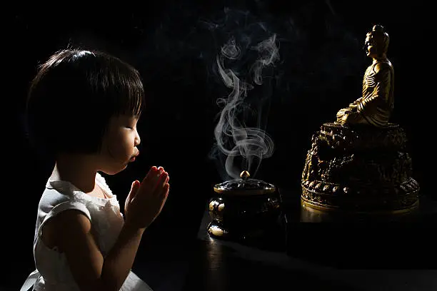 Photo of Asian Little Chinese Girl Praying in front of Buddha