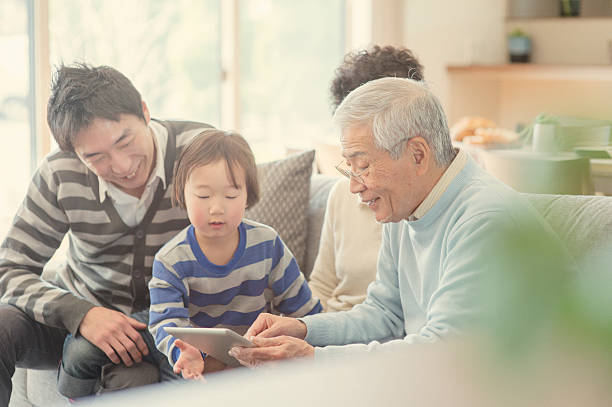 デジタルタブレットご家族とご一緒に自宅 - スマホ 日本人 ストックフォトと画像