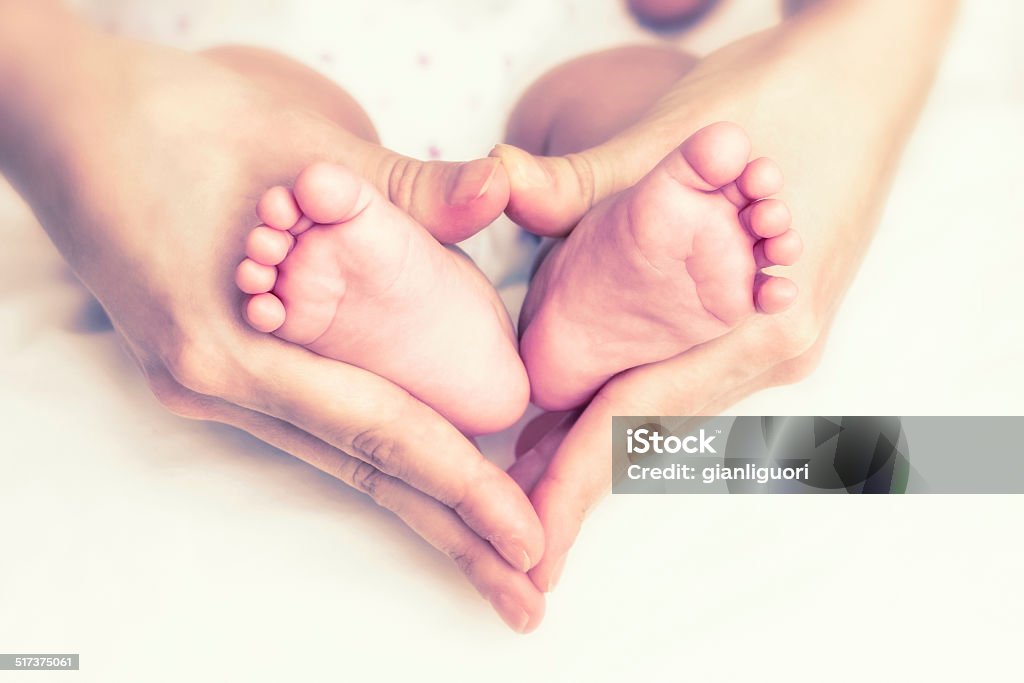 Pies de bebé en manos de la madre - Foto de stock de Bebé libre de derechos