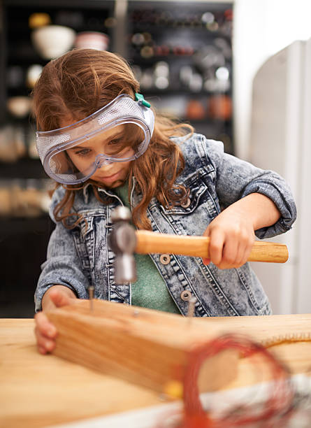 One of her many hobbies Shot of a little girl hammering nails into a block of wood girl with a hammer stock pictures, royalty-free photos & images