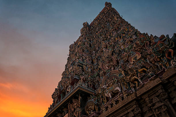 Meenakshi Temple One of towers of Meenakshi Temple against orange sky at sunset in Madurai, India. Night time.  menakshi stock pictures, royalty-free photos & images