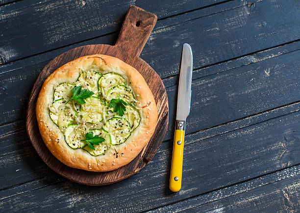 istock Zucchini pizza on rustic wooden cutting board 517378550