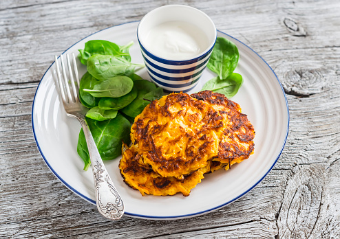 Sweet potato pancakes and fresh spinach on a light wooden background