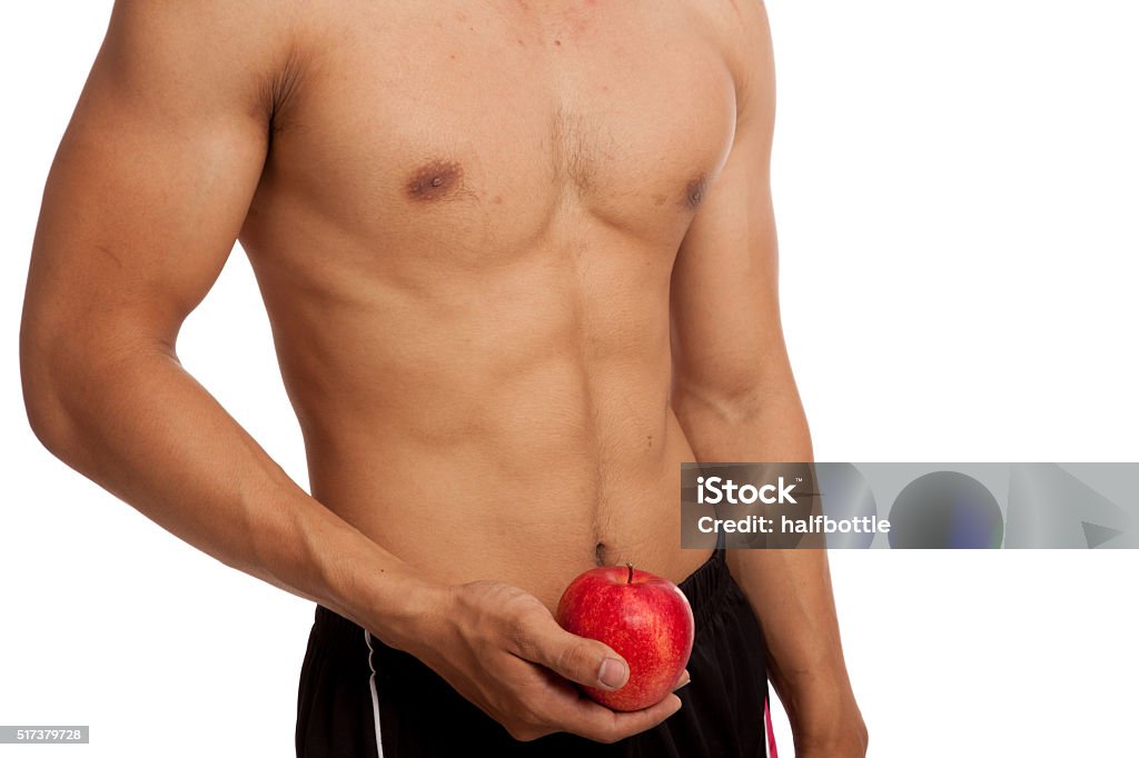 Muscular Asian man show six pack abs with red apple Muscular Asian man show six pack abs with red apple  isolated on white background Abdominal Muscle Stock Photo