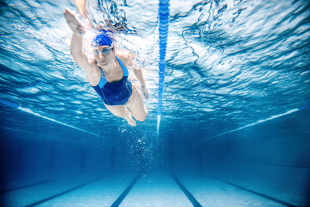 Woman Swimming Freestyle Under water shoot of a woman swimming freestyle in olympic pool swimming stock pictures, royalty-free photos & images