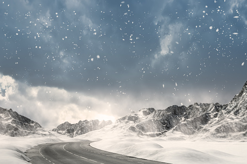 Snowfall on a country road leading through a winter mountain landscape.