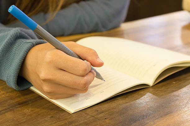 istock female hands with pen writing on book 517383442