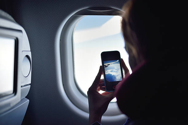 joven mujer tomando una foto en un avión - telephone cabin fotografías e imágenes de stock