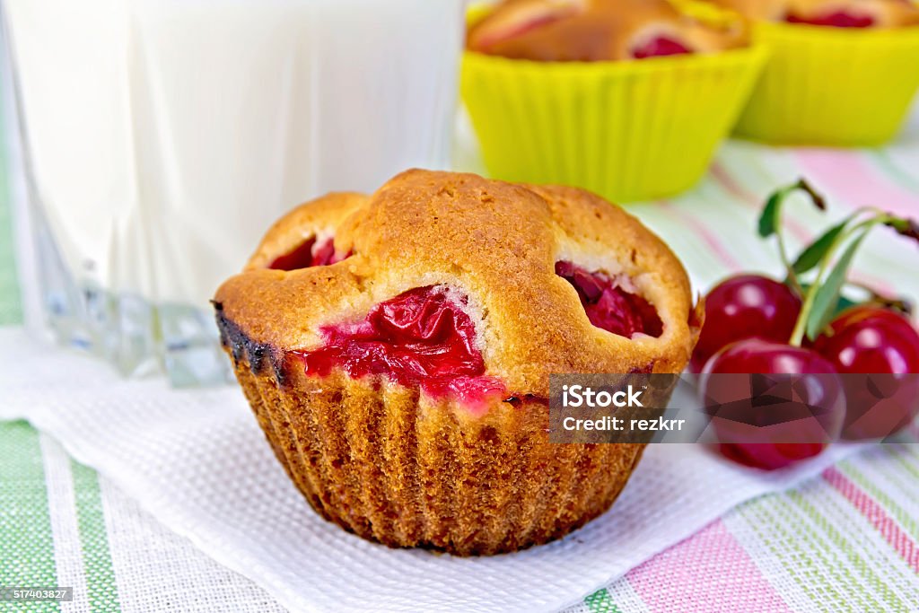 Cupcake with cherries and milk on napkin Cupcakes with cherries on a paper napkin, cherry, milk in a glass on a background of a linen tablecloth Backgrounds Stock Photo