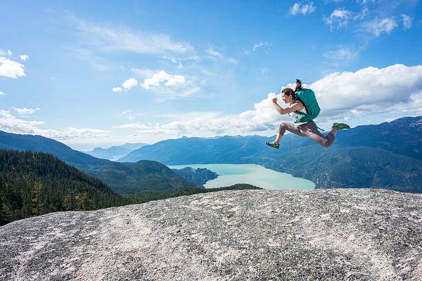 若い女性ハイカーバックパックジャンプで、荒野山頂、カナダ - outdoors exercising climbing motivation ストックフォトと画像