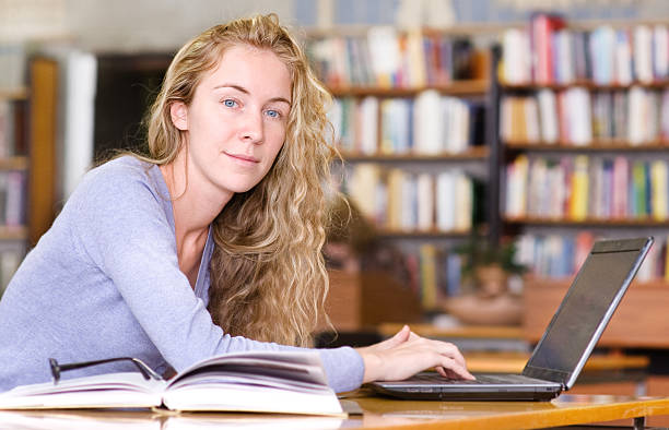 istock female student with laptop working in library. 517409120
