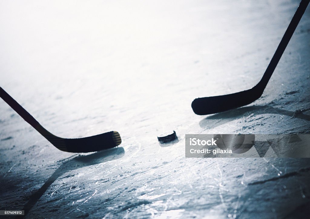 Ice hockey face off. Closeup of ice hockey players ready to hit the puck in a face off. Back lit shot, toned. Face Off - Sports Play Stock Photo