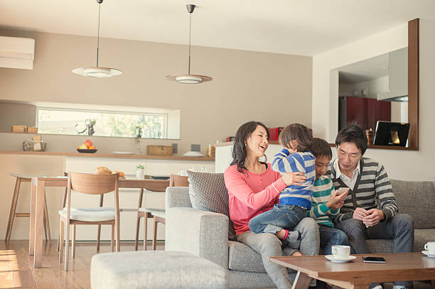 família relaxante na sala de estar - asian ethnicity child four people couple imagens e fotografias de stock