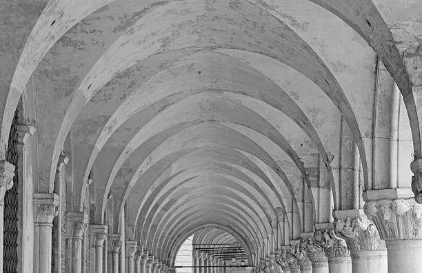Architectural perspective of a long covered walkway with columns and arches, creating a play of light and shadow